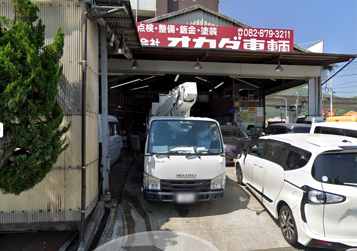 赤い看板が目印のオカダ車輌。整備工場の入口と車両